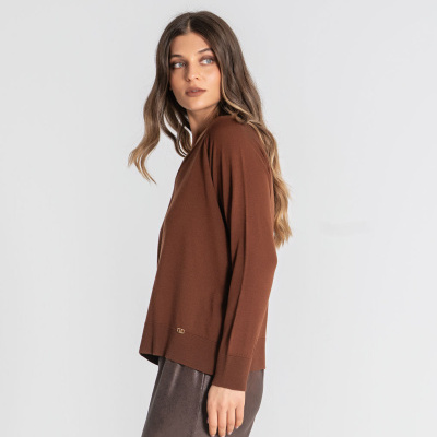 Mulher com camisola castanha de manga comprida e saia cinzenta