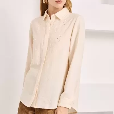 Camisa bege bordada com calças castanhas de veludo.
