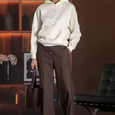 Mulher com hoodie branco e calças largas castanhas em ambiente interior