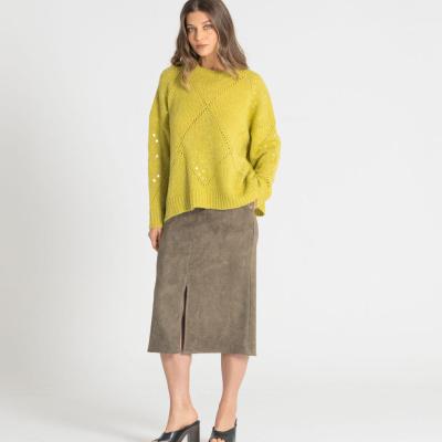 Mulher com suéter amarelo de malha, saia midi cinzenta com fenda e sandálias pretas de salto.