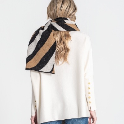 Mulher com camisola branca, jeans e cachecol listrado preto, castanho e bege vista de costas