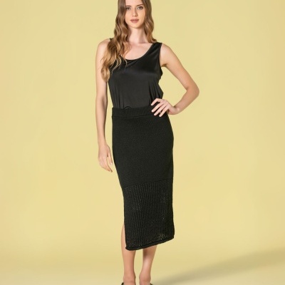 Mulher com blusa preta sem mangas e saia preta de malha