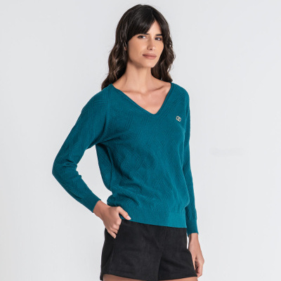 Mulher com camisola azul-petróleo e calções pretos num fundo branco