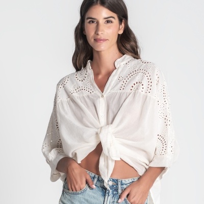 Mulher a usar camisola branca bordada e calças de ganga