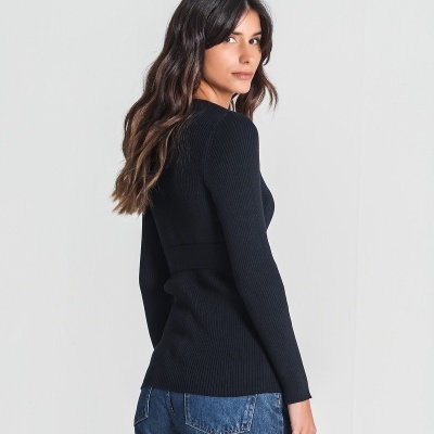 Mulher a usar camisola preta de malha canelada e calças de ganga azuis