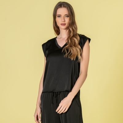 Conjunto de pijama preto de cetim com camisa e calças largas em fundo amarelo