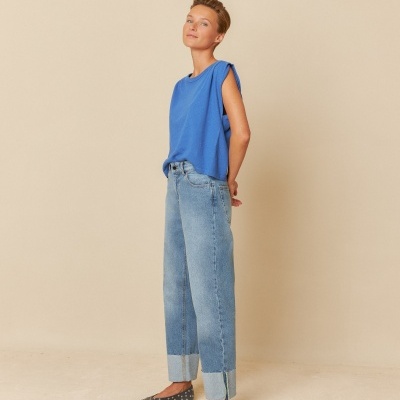 Mulher com roupa casual azul e jeans em fundo bege