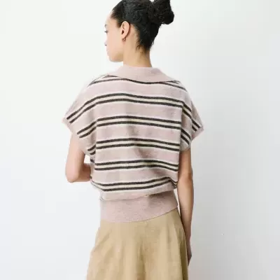 Camisa de malha rosa com riscas e saia bege vista de costas