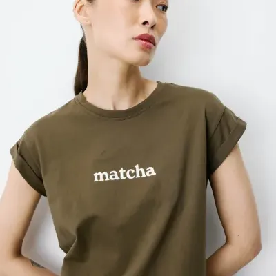 T-shirt verde oliva com a palavra matcha a branco usada por mulher