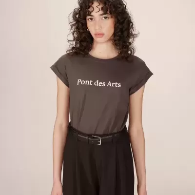 Mulher a usar t-shirt castanha escura com texto branco e calças pretas com cinto preto