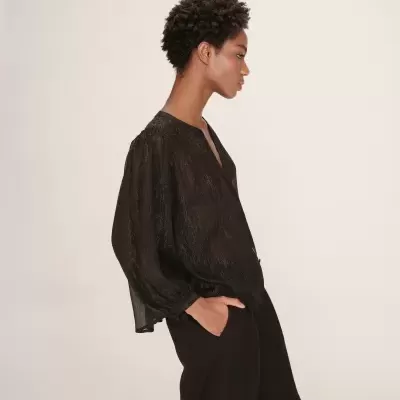 Blusa preta transparente com brilho e calças pretas vista de lado