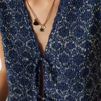 Blusa azul texturizada com laços à frente e colar de miçangas e pingentes