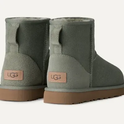Botas cinzentas de camurça com sola castanha e etiqueta UGG nas costas