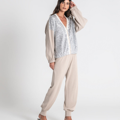 Mulher vestindo cardigan com lantejoulas prateadas, calças e sapatos bege