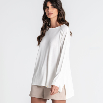Mulher com camisola branca e shorts bege