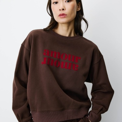 Mulher a usar sweatshirt castanha escura com texto vermelho amour amour