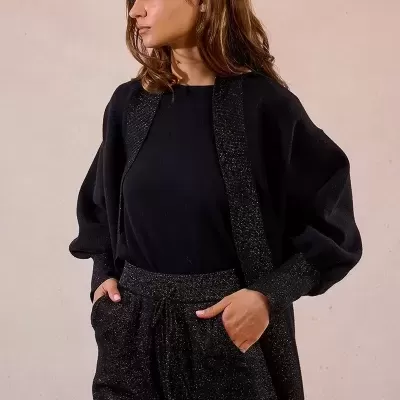 Mulher com conjunto de gola aberta brilhante e calças pretas com brilho