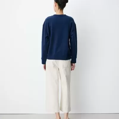 Pessoa com camisola azul escura e calças bege, vista de costas