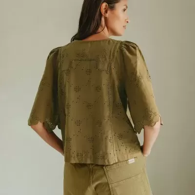 Blusa verde bordada com mangas bufantes e calções verdes de bolso grande vistos por trás