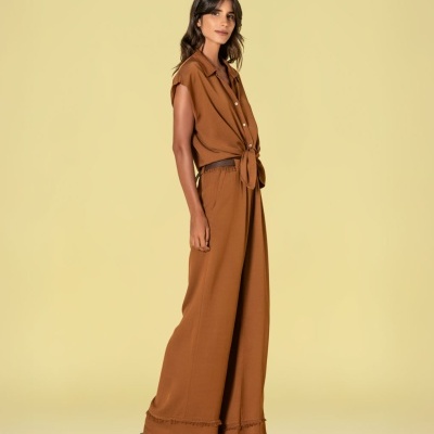 Conjunto castanho de camisa e calças largas femininas com sandálias pretas de salto.