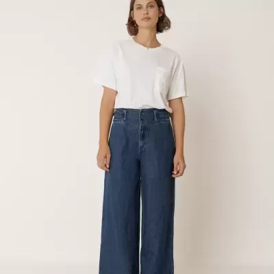 Mulher com t-shirt branca e calças de ganga largas azul-escuras