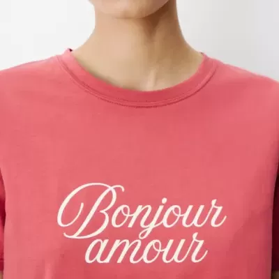 Pessoa a usar t-shirt rosa com texto branco Bonjour amour