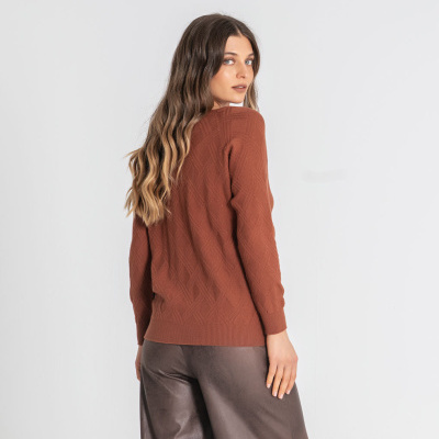Mulher com camisola castanha de malha e calças largas castanhas de tecido