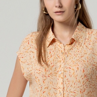 Blusa feminina bege com padrão laranja e castanho, botões brancos e gola clássica