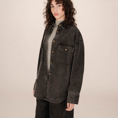 Blusão oversize em ganga preta com bolsos e botões numa modelo.