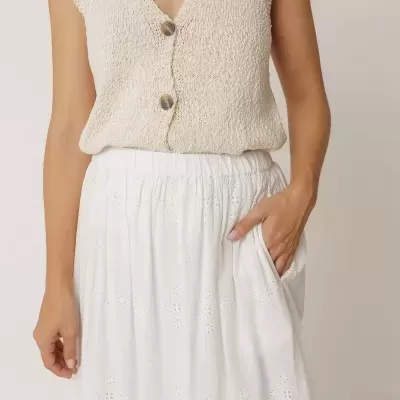 Colete de malha bege com botões e saia branca com bordados e bolso