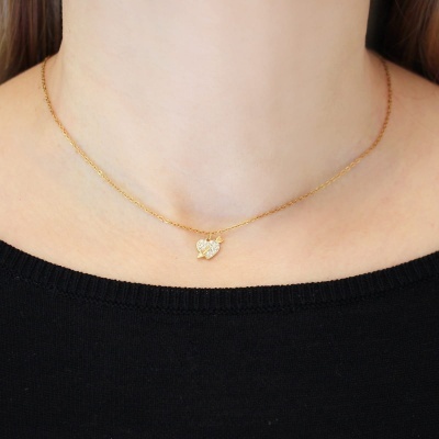 Colar dourado com pendente de coração em pescoço com camisa preta