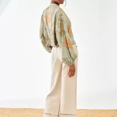 Mulher de costas com blusa floral e calças largas brancas