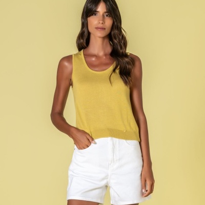 Mulher com regata amarela e calções brancos sobre fundo amarelo