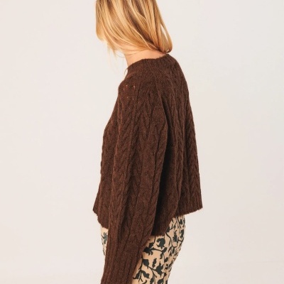 Mulher de perfil a usar camisola castanha de malha grossa com padrão de tranças