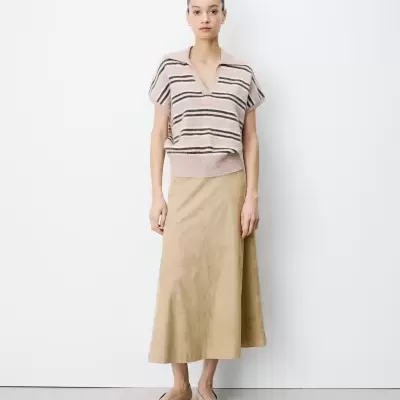 Mulher com blusa de malha às riscas bege e castanhas e saia midi bege