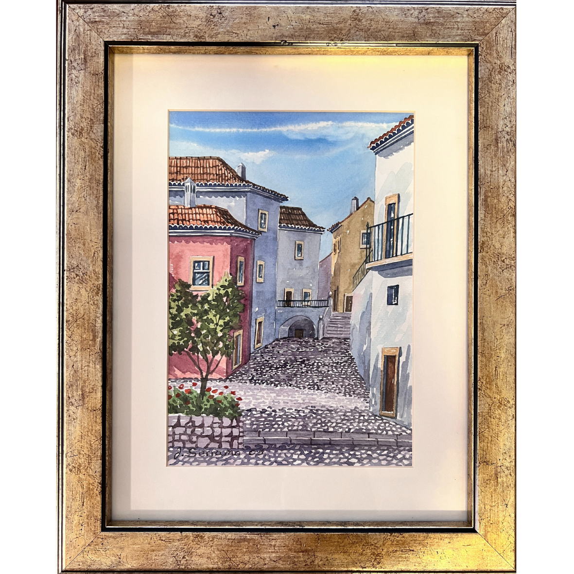 Pintura colorida de rua com casas e árvore, emoldurada em madeira dourada envelhecida