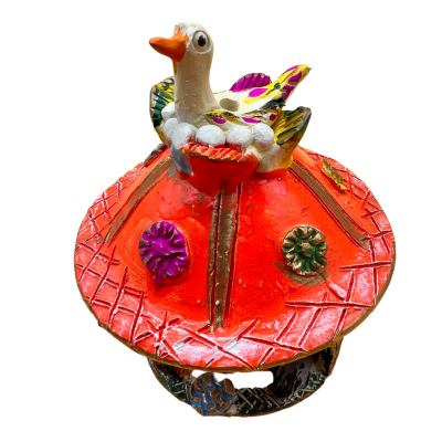 Figura decorativa em cerâmica com pato colorido sobre base vermelha com texturas e flores