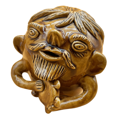 Cantil em cerâmica castanha com forma de rosto humano caricatural