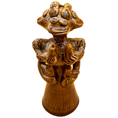 Escultura em cerâmica castanha com múltiplos olhos, bocas, mãos, e palavra INVEJA na base