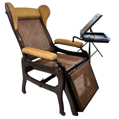 Cadeira reclinável de madeira com assento e encosto em palhinha e apoios castanhos, com suporte lateral para leitura ou tablete