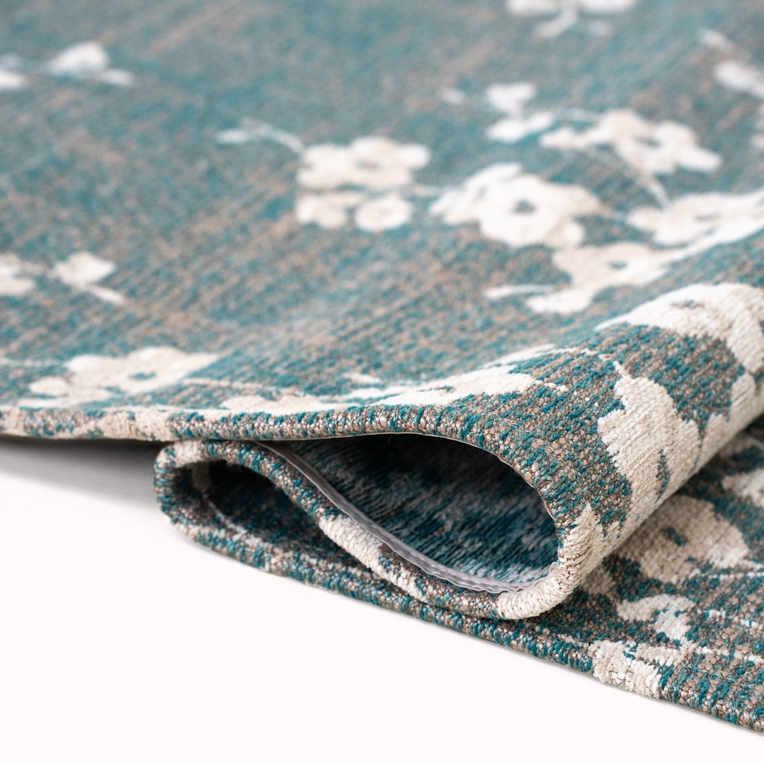 Tapete Almond Chenille Tapete azul esverdeado com padrão floral branco dobrado sobre fundo branco