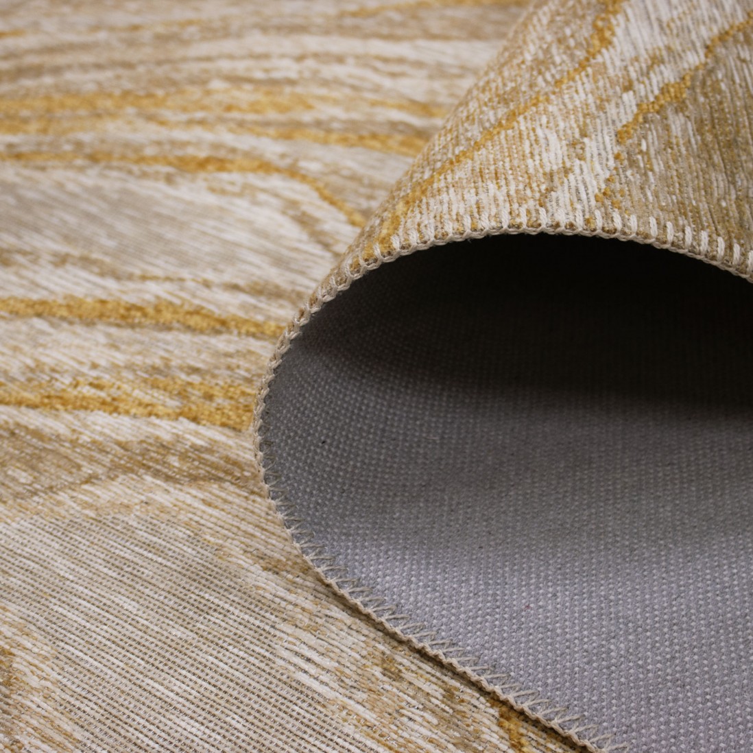 Tapete Adore Tapete bege e dourado com base cinza dobrado mostrando a textura e reverso.