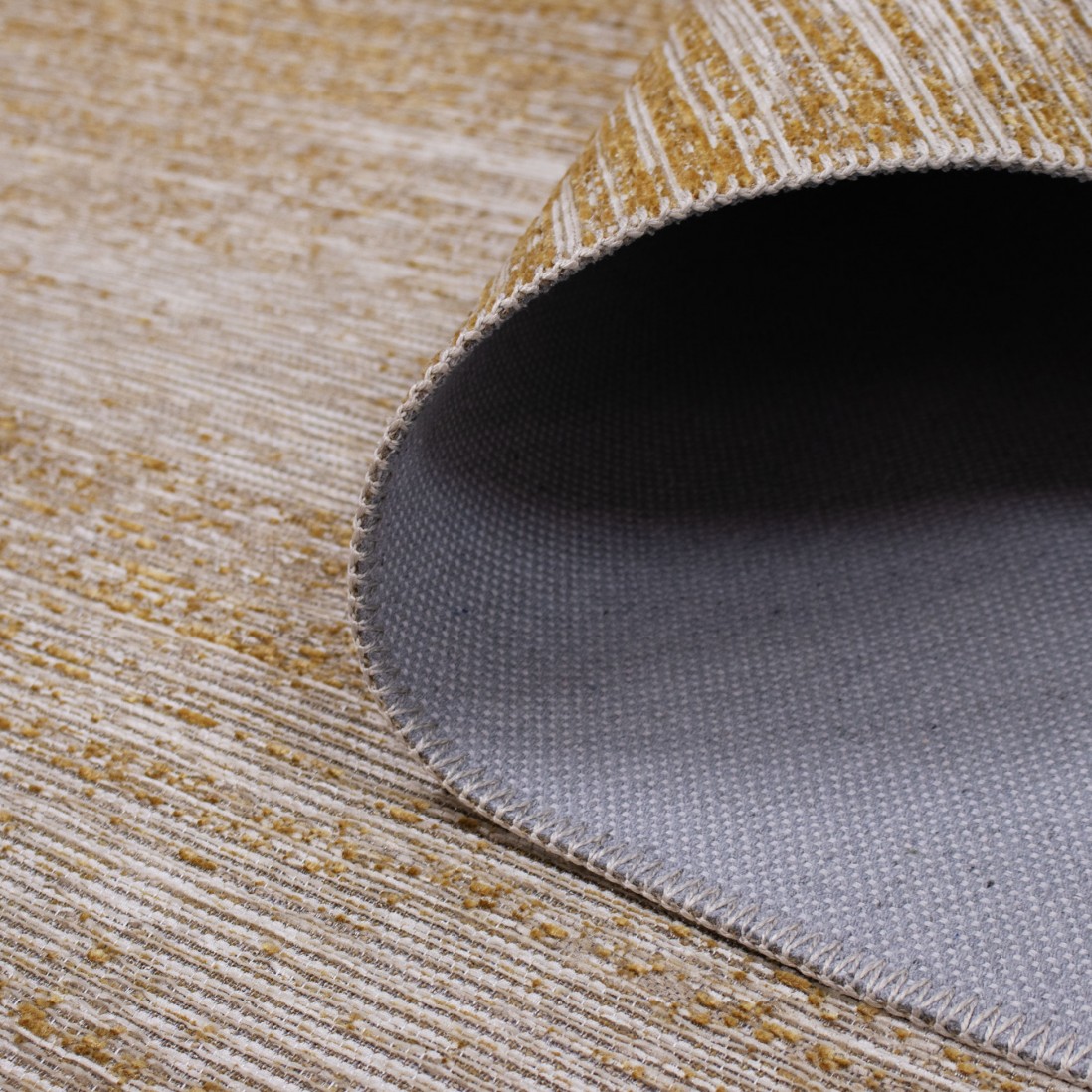 Tapete Adore Tapete riscado bege e dourado com verso cinzento sobre piso de madeira