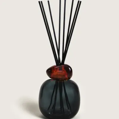 Difusor de aroma de vidro azul escuro com tampa vermelha e varetas pretas