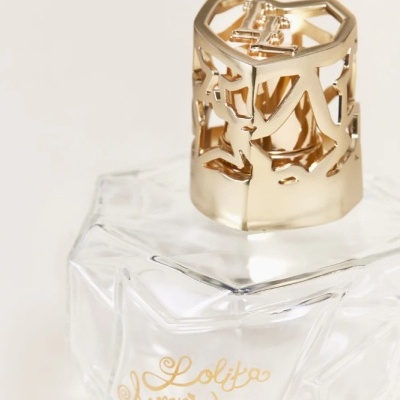 Frasco de perfume transparente com tampa dourada e texto 'Lolita Lempicka'