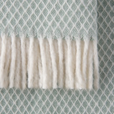 Manta azul com padrão geométrico branco e franjas.