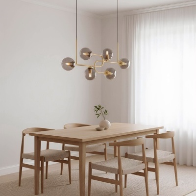 Mesa de jantar em madeira clara com quatro cadeiras e candeeiro suspenso com globos de vidro fumado