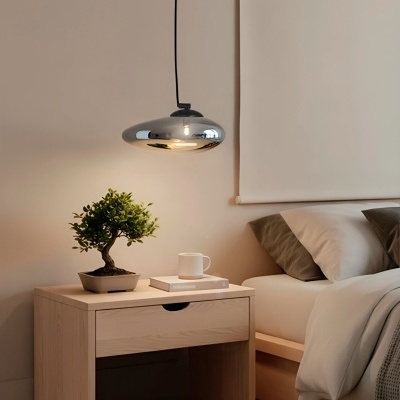 Mesa de cabeceira com bonsai e lâmpada pendente ao lado de cama arrumada