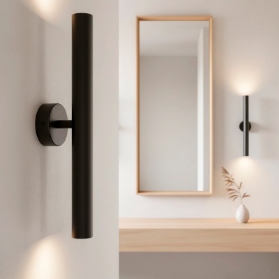 Arandela preta cilíndrica com luzes na parede branca junto a mesa de madeira e espelho