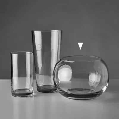 Três vasos de vidro transparente em diferentes formas sobre uma mesa